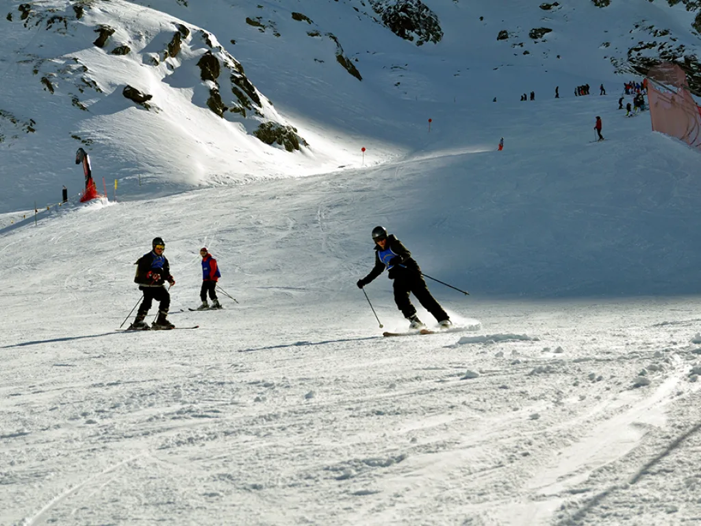 Zwei Skifahrende auf dem Hang unterhalb der Felsen.